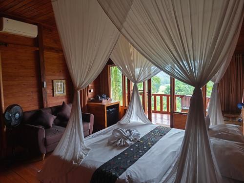 シデメンにあるManuk Dewata Villaのベッドルーム1室(カーテン付きのベッド1台、ソファ付)