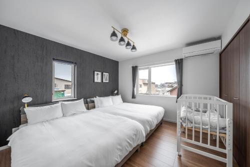 a bedroom with a large white bed and a crib at Pregio Asahikawa in Asahikawa