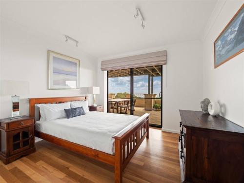 Un dormitorio con una cama y una puerta corrediza de vidrio. en Ocean Views - Refined Hilltop Residence by the Sea, en Yallingup