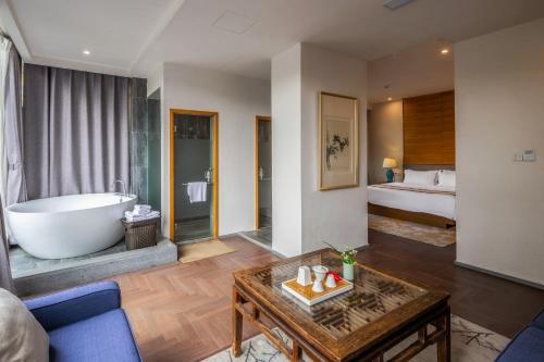 a living room with a tub and a bedroom at Guilin HeShe Lakeside Resort-Free pick up train station stay two nights in Guilin