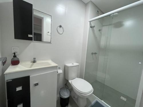 a white bathroom with a toilet and a glass shower at Queridinho da praia de palmas in Governador Celso Ramos