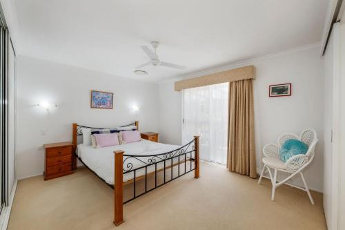 a bedroom with a bed and a chair and a window at 22 Bussey Street in Bargara