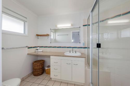 a bathroom with a sink and a glass shower at 22 Bussey Street in Bargara