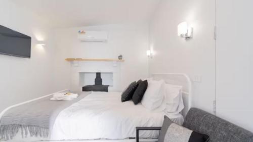 EpsomNouvelle Studio的白色卧室设有白色的床和壁炉