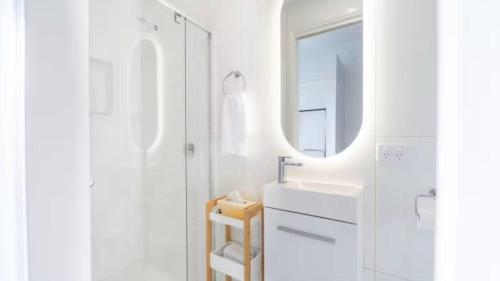 EpsomNouvelle Studio的一间白色浴室，配有洗手池和镜子。
