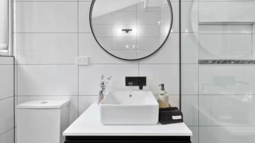 a white bathroom with a sink and a mirror at Vineyard Accommodation in Dorrien