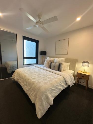 une chambre avec un lit blanc avec un ventilateur de plafond dans l'établissement Avalon Maroochydore, à Maroochydore