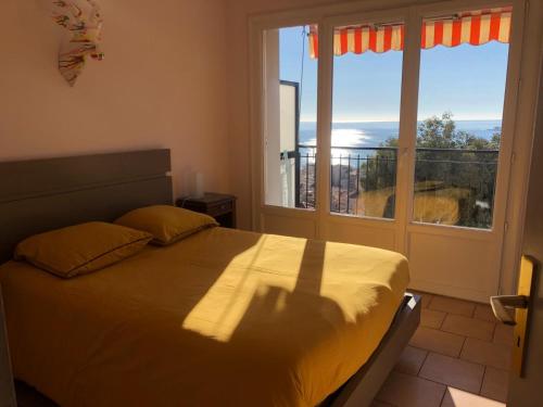 een slaapkamer met een bed en een groot raam bij Appartement spacieux à 10 minutes de la plage, vue mer in Menton