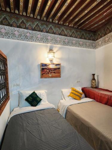 two beds in a room with a ceiling at Riad el Anaqa in Fez