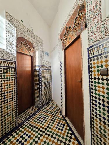 a bathroom with a wooden door and a tiled floor at Riad el Anaqa in Fez