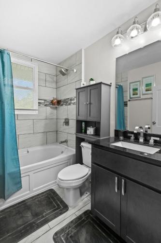 a bathroom with a tub and a toilet and a sink at Spacious Cottage near Airport, Hospitals, and Highways in Bel-Ridge