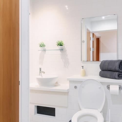 a white bathroom with a sink and a toilet at The Central Suite in Manchester