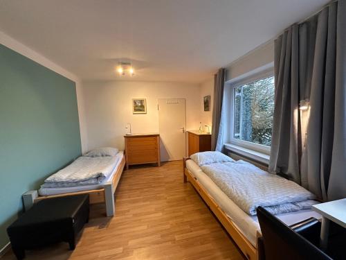 two beds in a room with a window at Pension Hostel Herdorf in Herdorf
