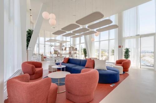 a living room with a blue couch and orange chairs at River Residenz Basel&Huningue in Huningue