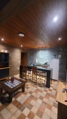 a large kitchen with a table and a refrigerator at Chalé Gravatinha in Mucugê