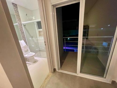 a bathroom with a glass door leading to a toilet at Mansão Maretti in Bertioga