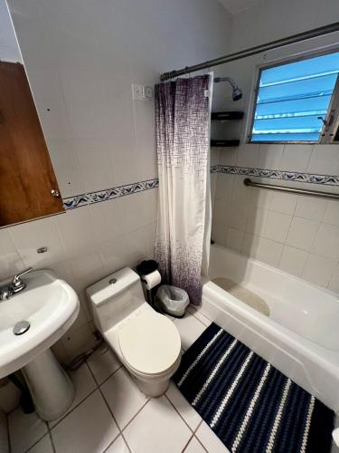 a bathroom with a toilet and a sink and a tub at Beach Hub 7 Mins to Airport in Carolina