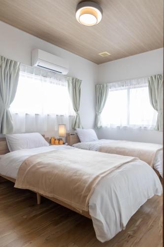 two beds in a bedroom with two windows at 勝山駅徒歩1分 恐竜博物館車5分スキージャム15分 BBQ可能 シアタールーム Kidsルーム完備 駅前好立地 in Katsuyama