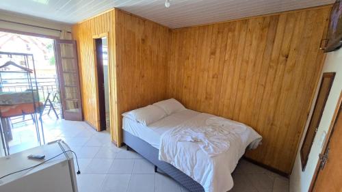 a bedroom with a bed in a wooden wall at Pousada Miniférico in Campos do Jordão