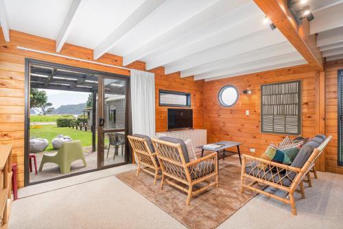 a living room with rocking chairs and a patio at Hosts on the Coast Hahei Sands Villa A in Hahei