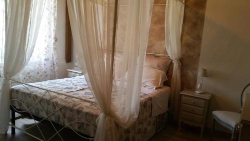Badia a RuotiにあるCasa Rominaのベッドルーム(白いカーテン付きの天蓋付きベッド1台付)