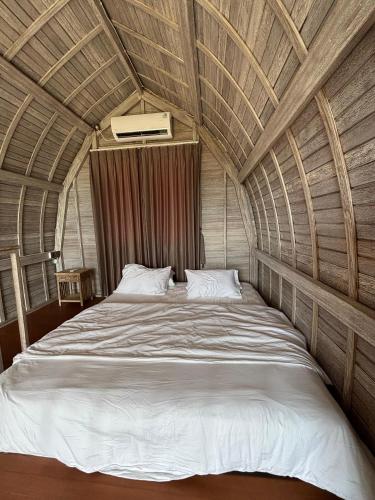 a large bed in a room with a wooden ceiling at CARROLINE homestay ricefield in Kapal