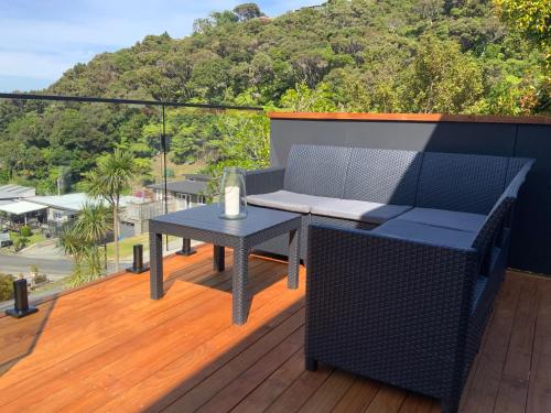 a patio with a table and a chair on a deck at Tuis Nest, family beach bach at Opito Bay in Kerikeri