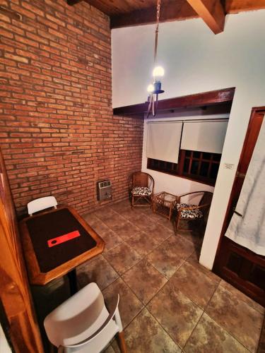 a room with a table and chairs and a brick wall at Cabañas Lorelei in Villa General Belgrano