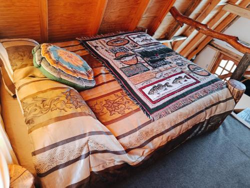 CABAÑA RAIZ INDOMITA PINTO Ñuble : سرير عليه لحاف في غرفه