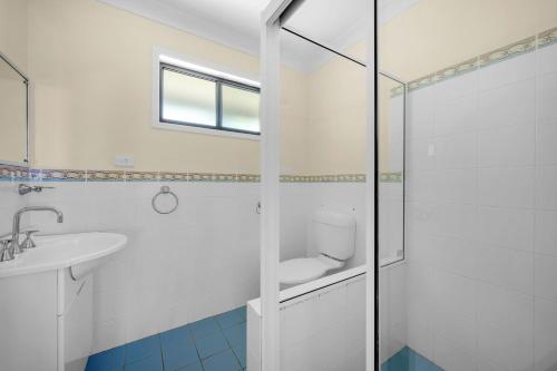 Un baño blanco con inodoro y lavabo. en Beachfront Unit - Belle Escapes Jervis Bay, en Vincentia