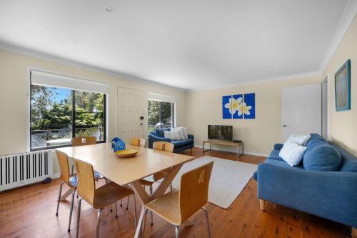 a living room with a table and a blue couch at Beachfront Unit - Belle Escapes Jervis Bay in Vincentia