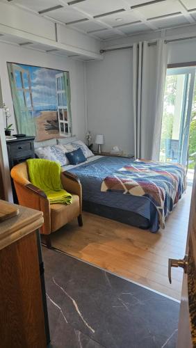 a bedroom with a bed and a chair and a painting at Suite 1 Flèche du fjord vue Saguenay Monts Valin in Saint-Fulgence
