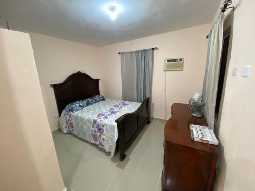 Un dormitorio con una cama, una cómoda y una mesa. en Casa amarilla, en La Romana