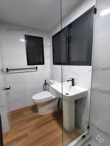 a white bathroom with a toilet and a sink at Turtle Nest in Hua Hin