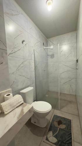 a white bathroom with a toilet and a shower at Pousada Atalaia in Cuiabá