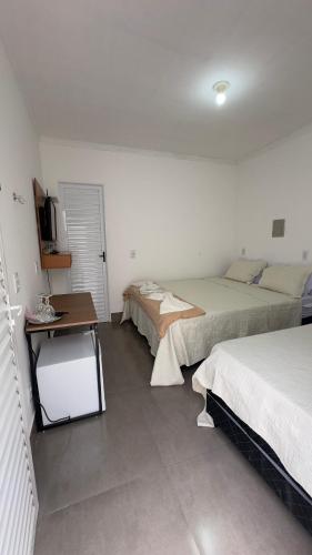 a bedroom with two beds and a desk in it at Pousada Atalaia in Cuiabá