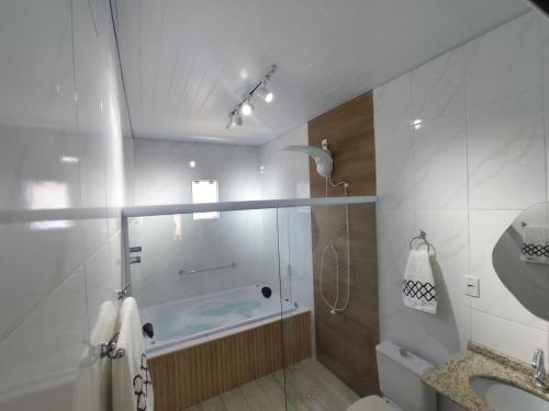 een badkamer met een douche, een wastafel en een bad bij Loft em Florianópolis à 1km da praia in Florianópolis