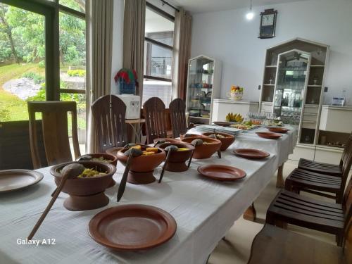 Una mesa larga con platos y cuencos de comida sobre ella. en Pinnacle Life, en Matale