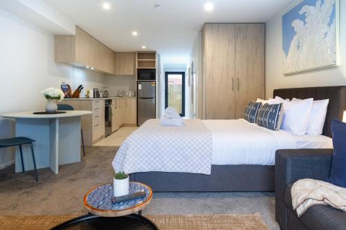 a bedroom with a large bed and a kitchen at Modern Studio Near Stadium, Dining & City Fun in Christchurch