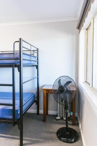 a room with a fan and a desk and bunk beds at Warra Gnan Coastal Camp in Warrnambool