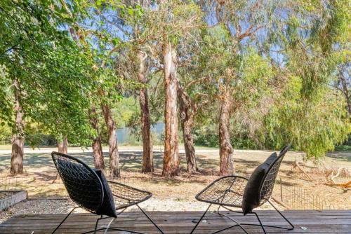 two chairs sitting on a wooden deck with trees at Romantic Lakefront Luxury - Spa Bath, Fireplace, King Bed in Daylesford