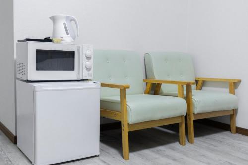 two chairs and a microwave on top of a refrigerator at ゴーゴーマリンホテル 東京千葉館山 in Tateyama