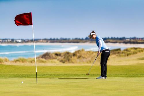 a woman playing golf next to a red flag at Central Motel Port Fairy in Port Fairy