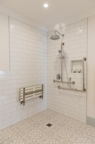 a white tiled bathroom with a bench and a shower at Criterion Hotel Napier in Napier