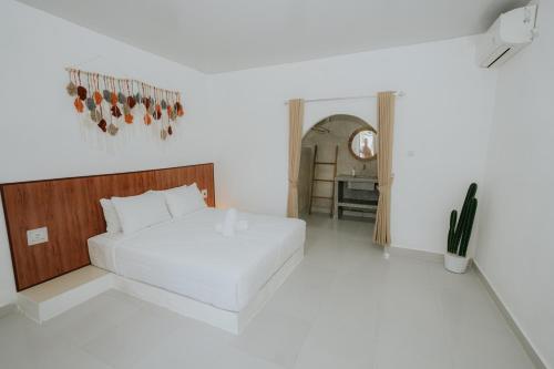 a white bedroom with a bed and a table at MY BOO PRIVATE by DRAGONFLY in Nusa Penida