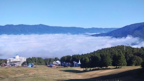 a view of a field with clouds in the mountains at Red Gate Lodge in Kijimadaira