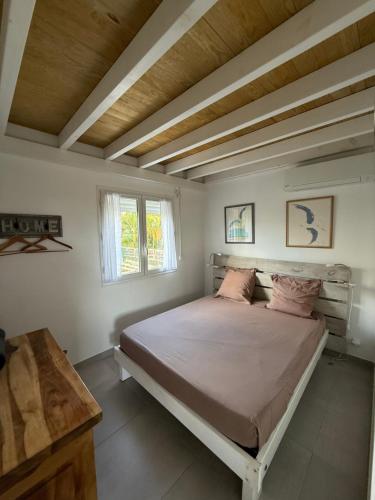 a bedroom with a bed and a wooden ceiling at Appartement neuf a 150 metres de la mer wifi in Le Diamant