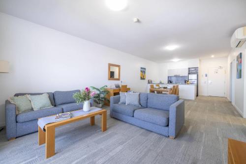 a living room with two blue couches and a table at MainStay Suites Mackay in Mackay