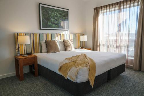 a large bed in a hotel room with a large window at MainStay Suites Whyalla in Whyalla
