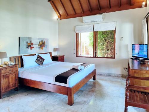 a bedroom with a large bed and a television at Villa Diana Bali 14 Bedrooms in Seminyak
